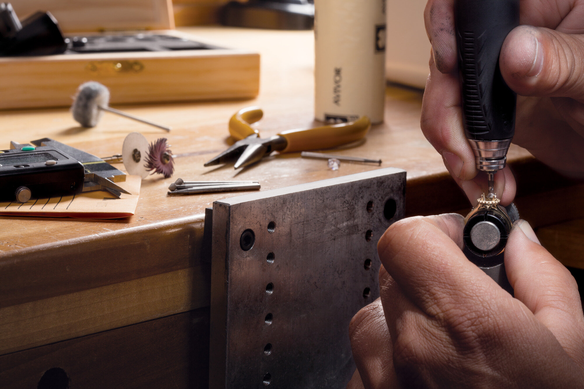 Jeweler working on a ring with a rotary tool at the bench